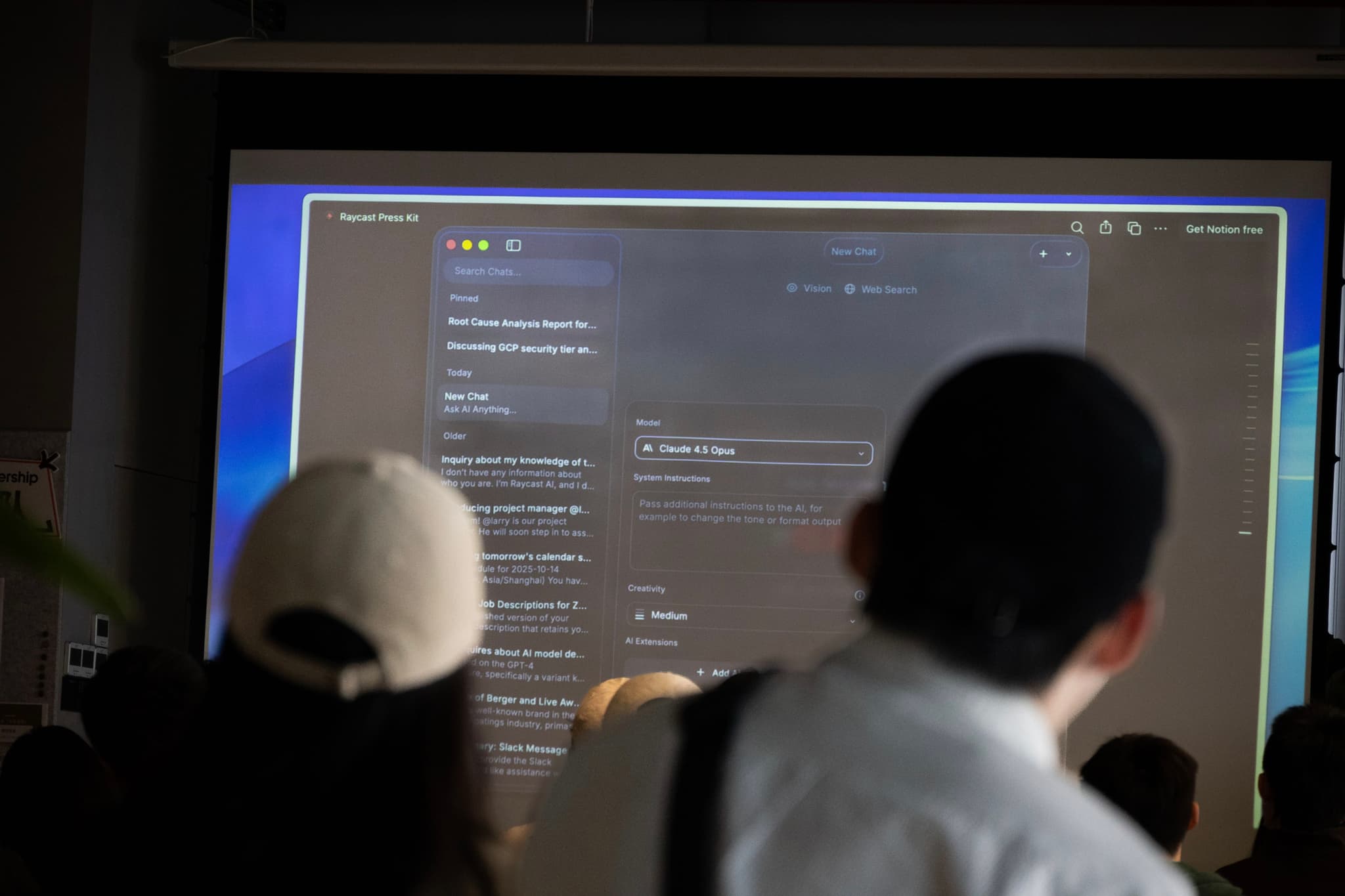 Two people seen from behind watching a projected computer screen with code and settings in a classroom
