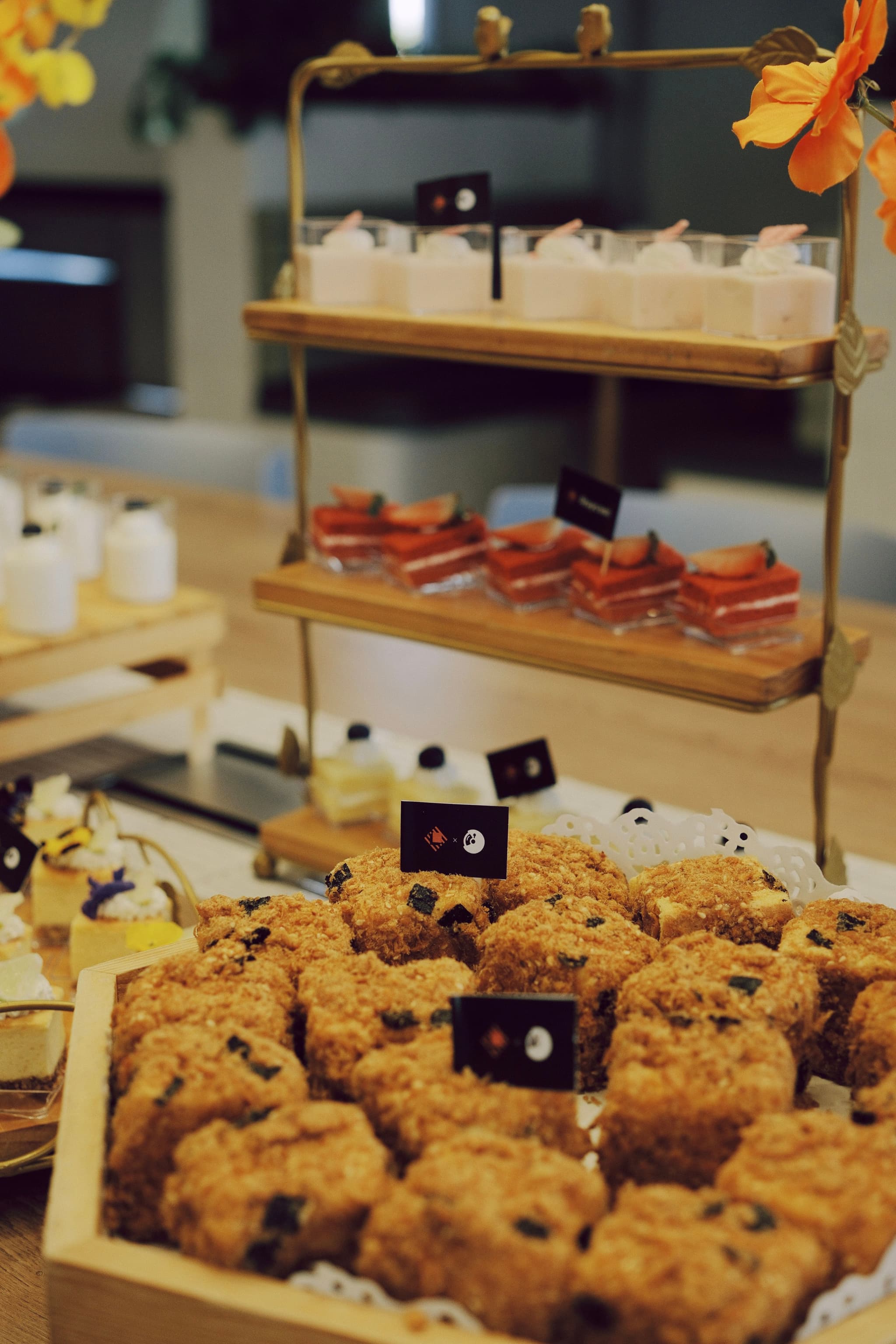 Assorted pastries and desserts arranged on a tiered wooden display stand with small label cards
