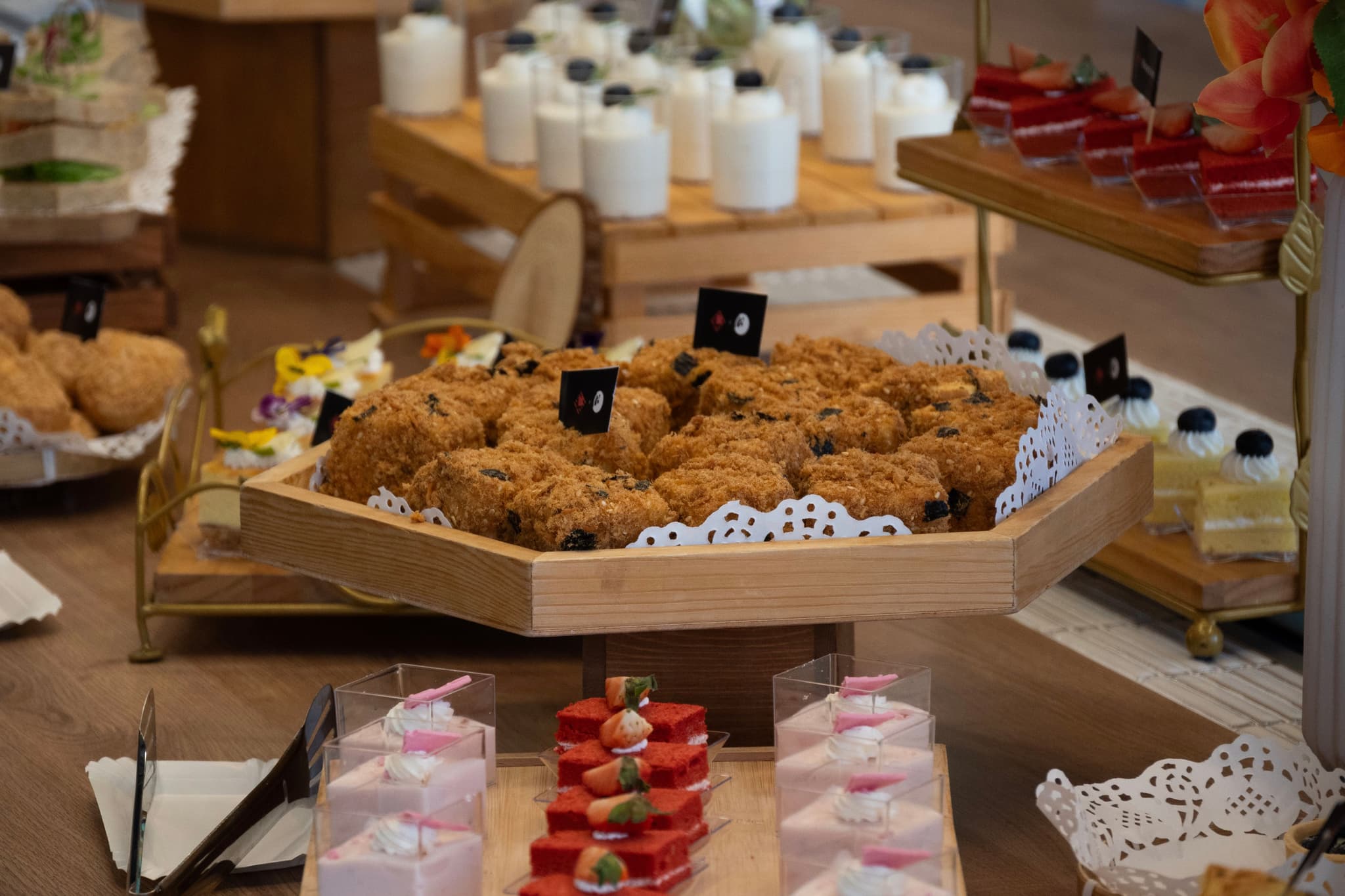 Assorted pastries and desserts arranged on a buffet table with drinks in the background