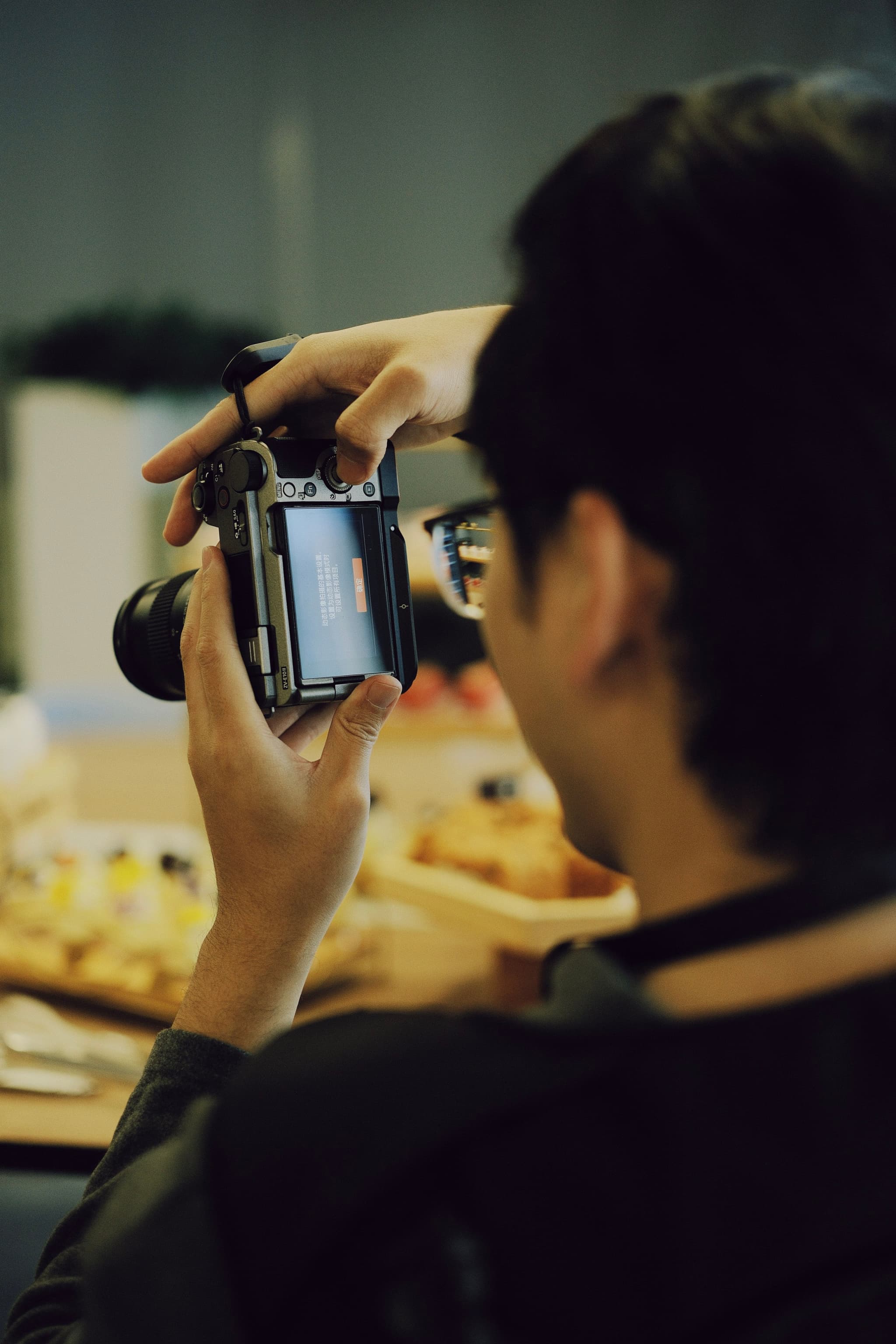 Person holding a camera and photographing a table of food indoors
