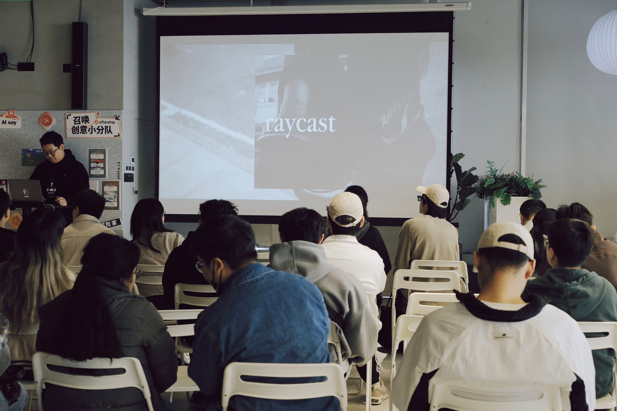 Audience seated in a meeting room watching a presentation on a projected screen