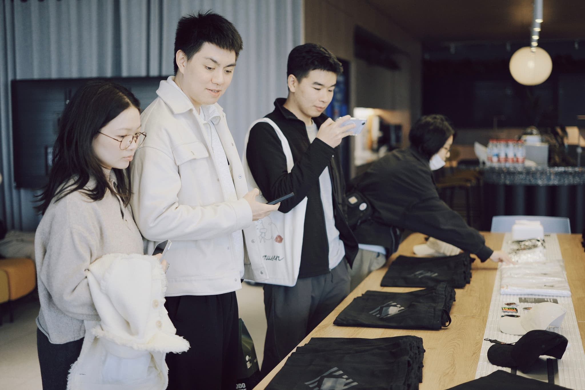 Three people in aprons working together behind a cafe counter with trays and equipment
