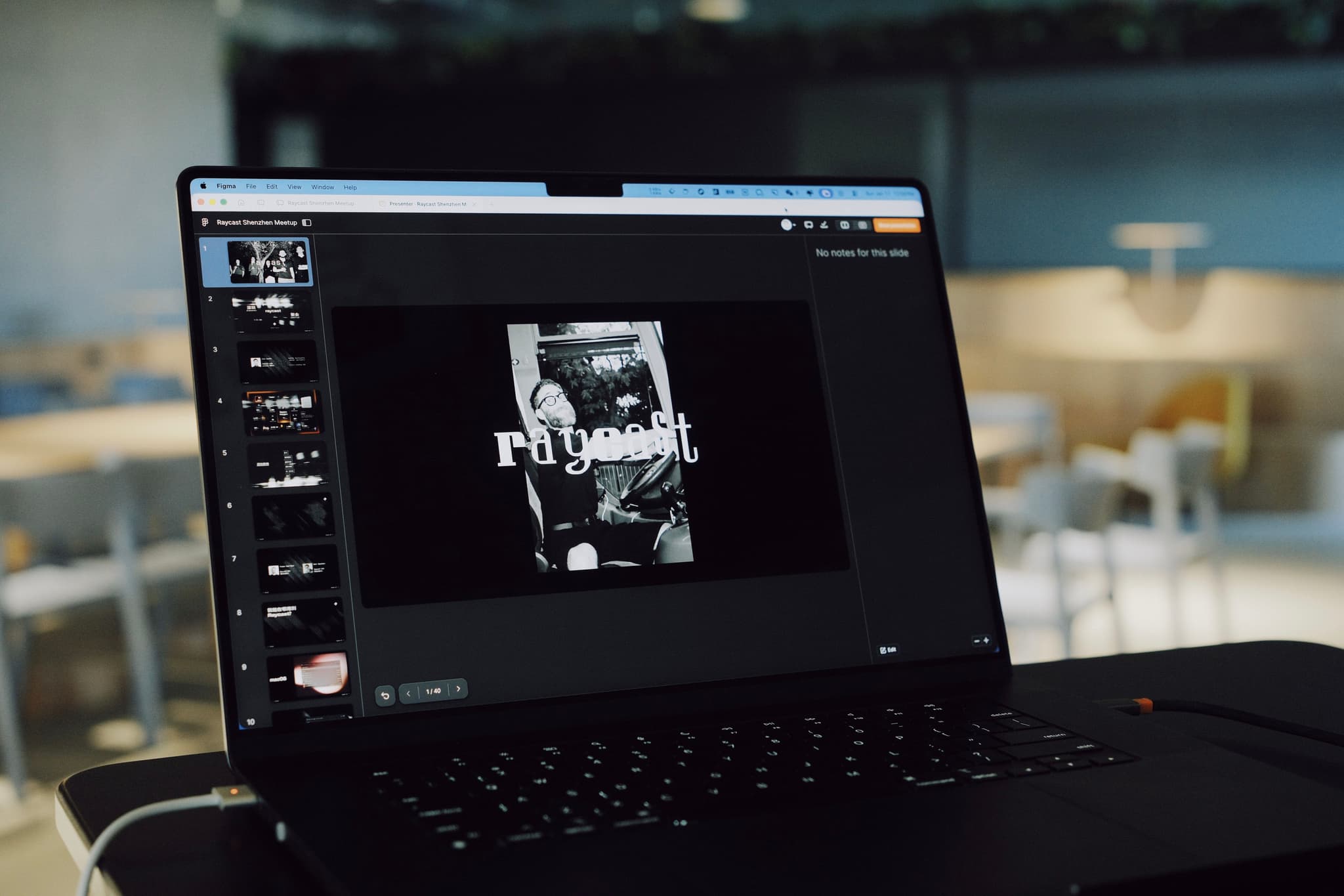 Open laptop on a table displaying a slide deck in a conference or auditorium setting with empty seating in the background