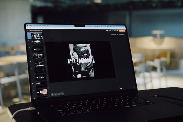 Open laptop on a table displaying a slide deck in a conference or auditorium setting with empty seating in the background