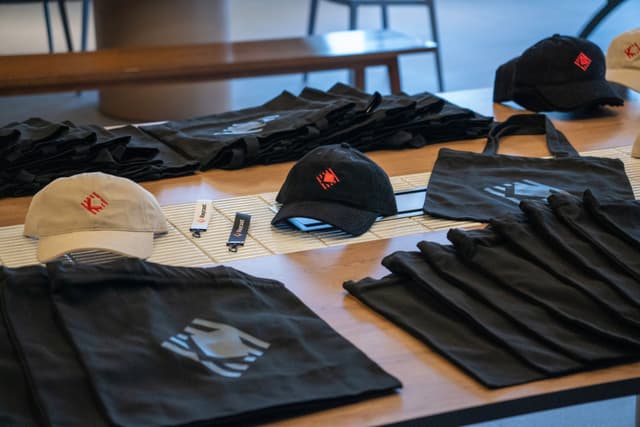 Assorted branded apparel laid out on a table including caps gloves and folded shirts with tags