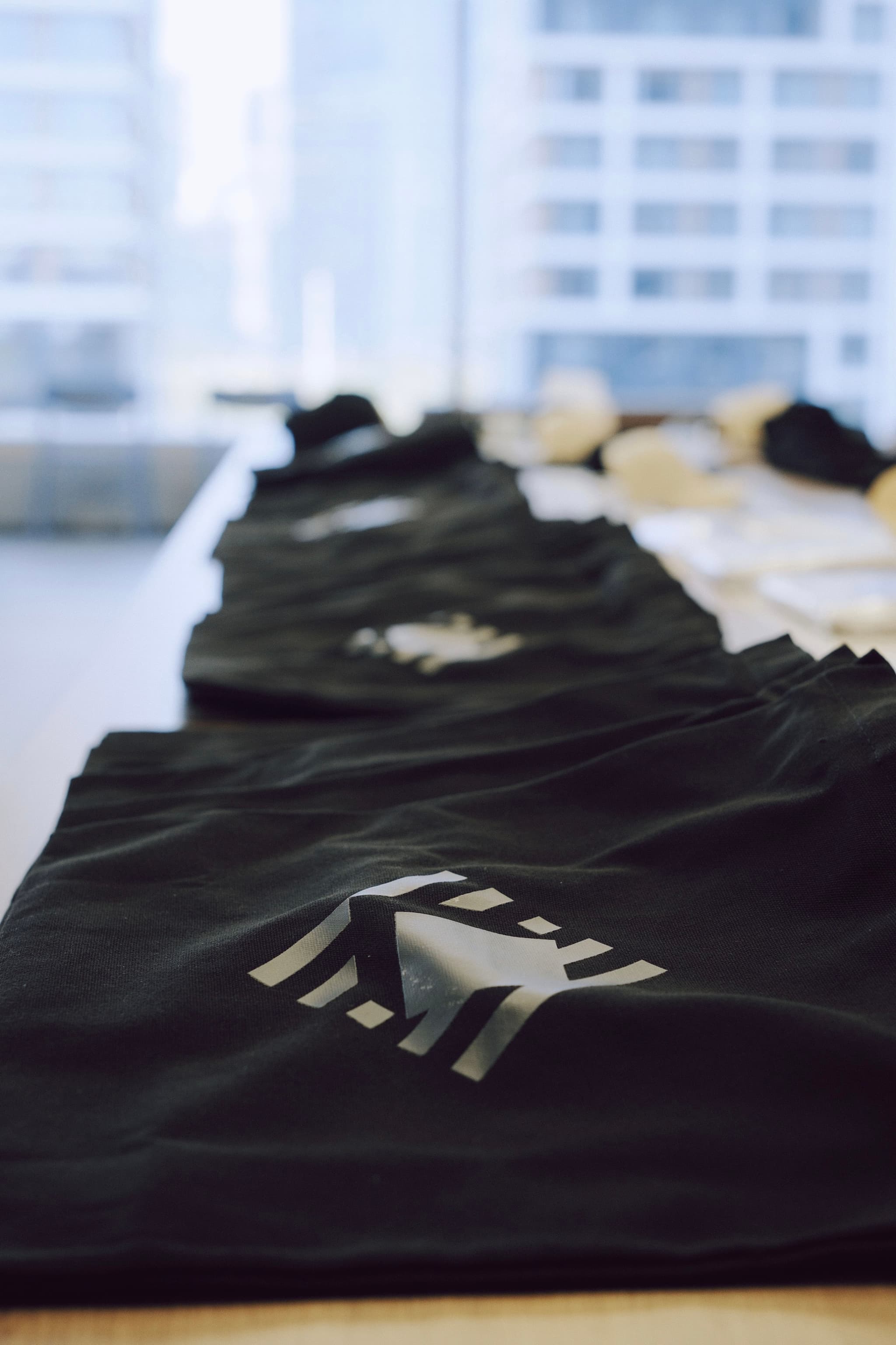 Stack of black conference tote bags laid out on a table in an indoor venue