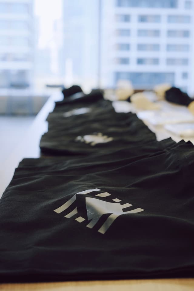 Stack of black conference tote bags laid out on a table in an indoor venue