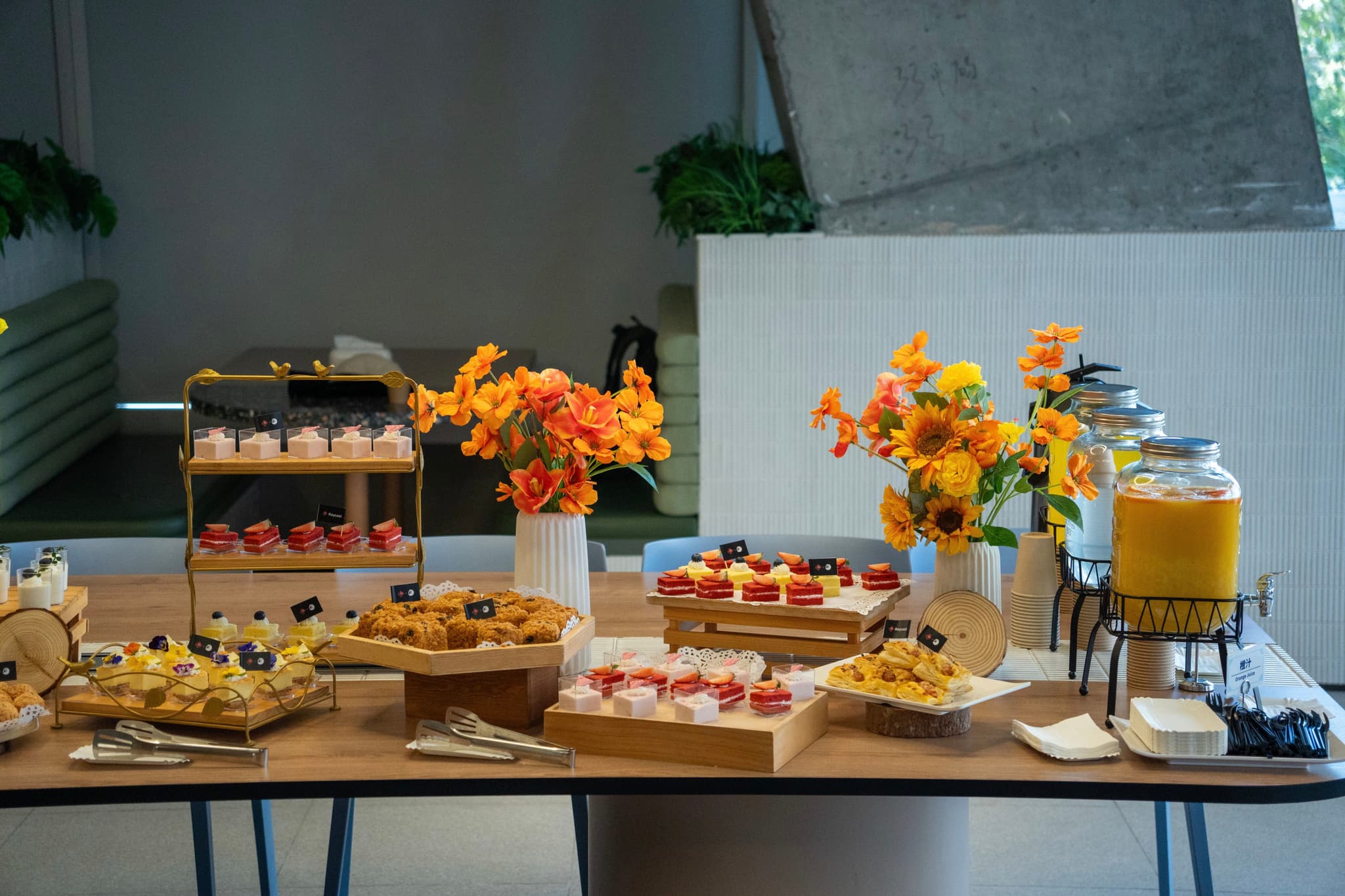 Indoor buffet table with pastries finger foods and drinks decorated with bright flower arrangements