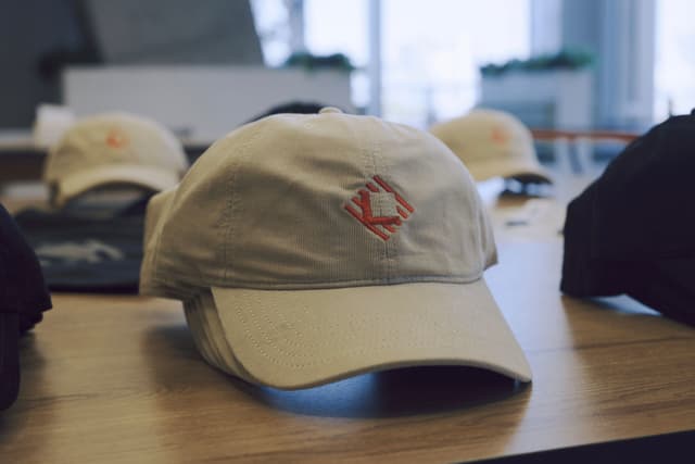 Several baseball caps arranged on a table indoors with a beige cap in the foreground