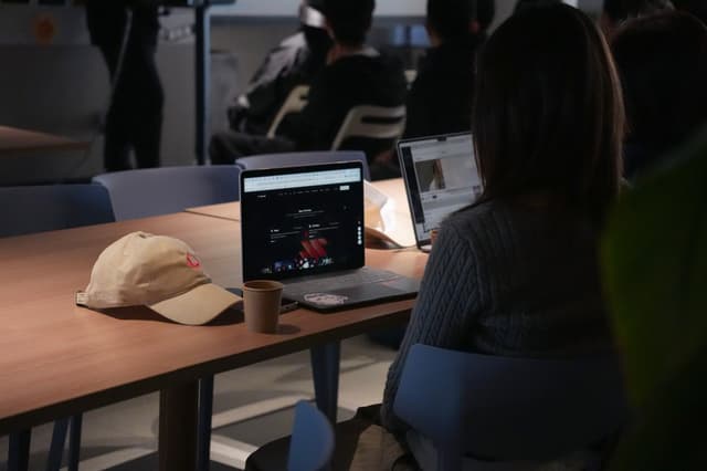 People seated at a table watching a tablet display during a classroom or workshop session