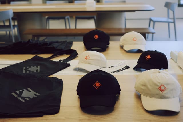 A table display of conference swag including tote bags and baseball caps