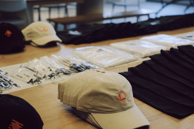 Tabletop display of conference giveaways including tote bags hats and printed materials