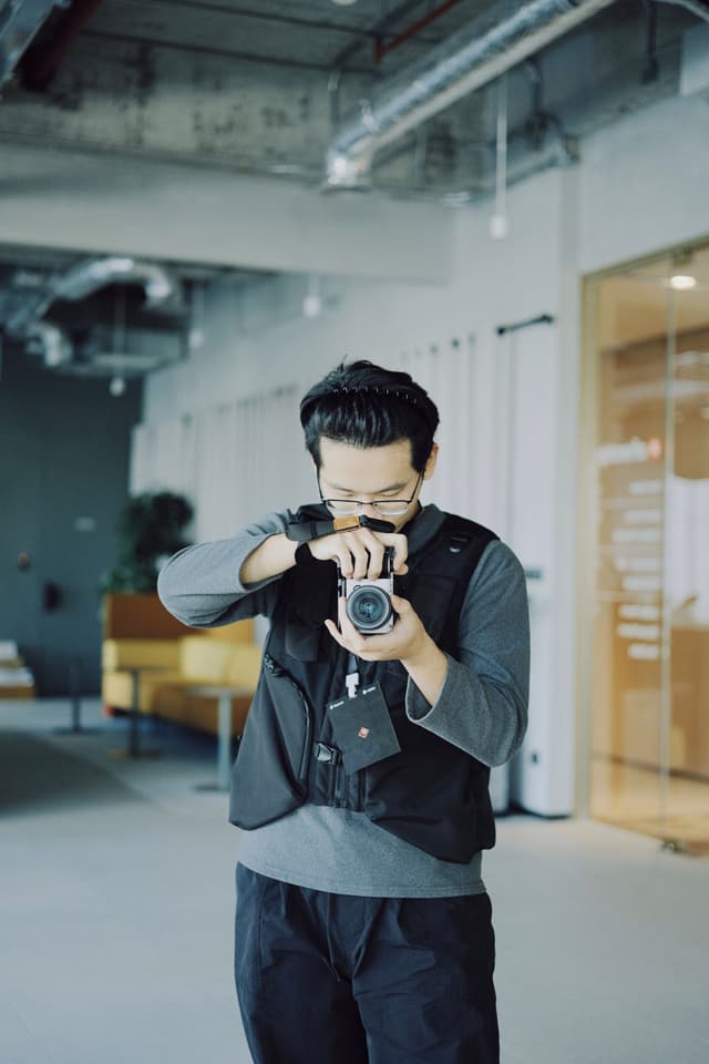 Person holding a camera up to their face taking a photo indoors in a modern industrial space
