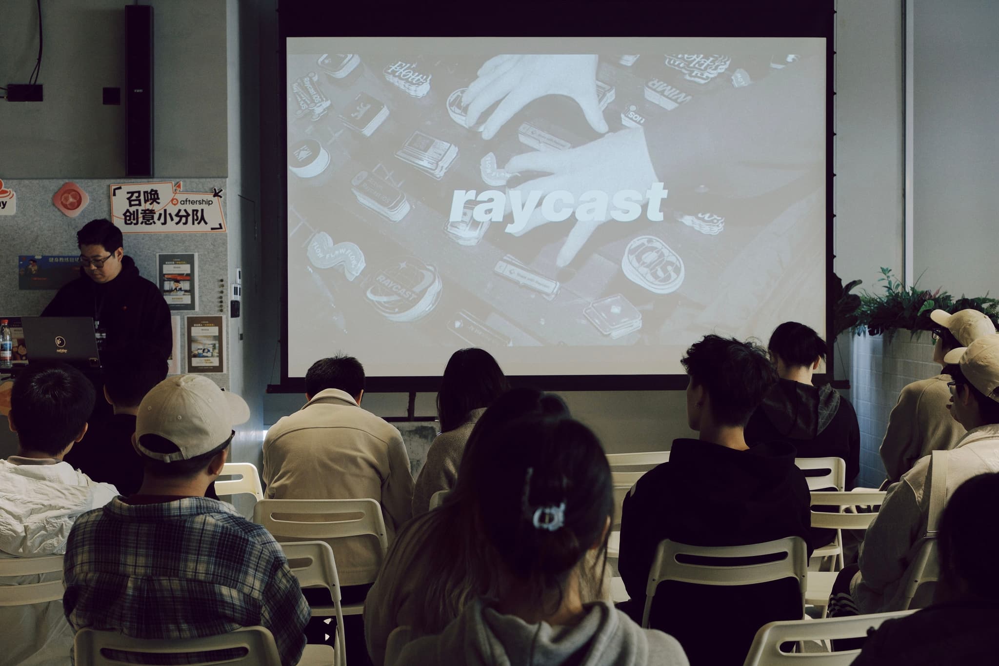 Audience seated at a meetup watching a presentation on a projector screen
