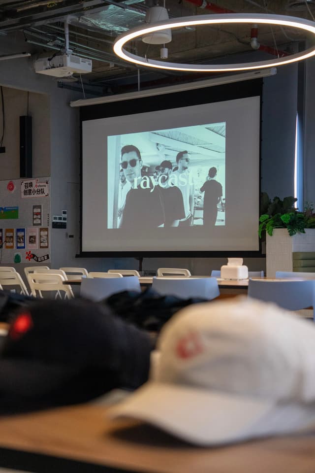 Conference room with people presenting slides on a projector screen and attendees seated at tables