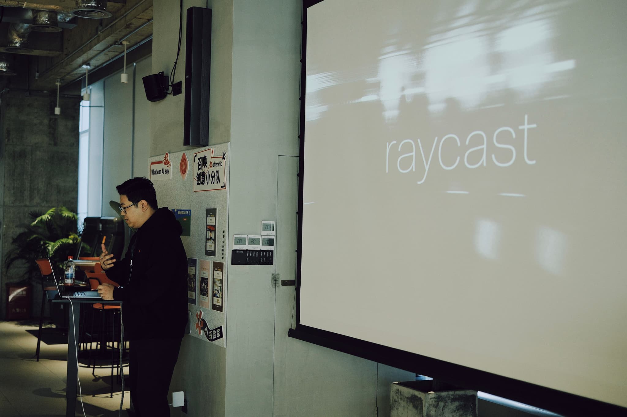 Presenter stands beside a large projected screen in a conference room